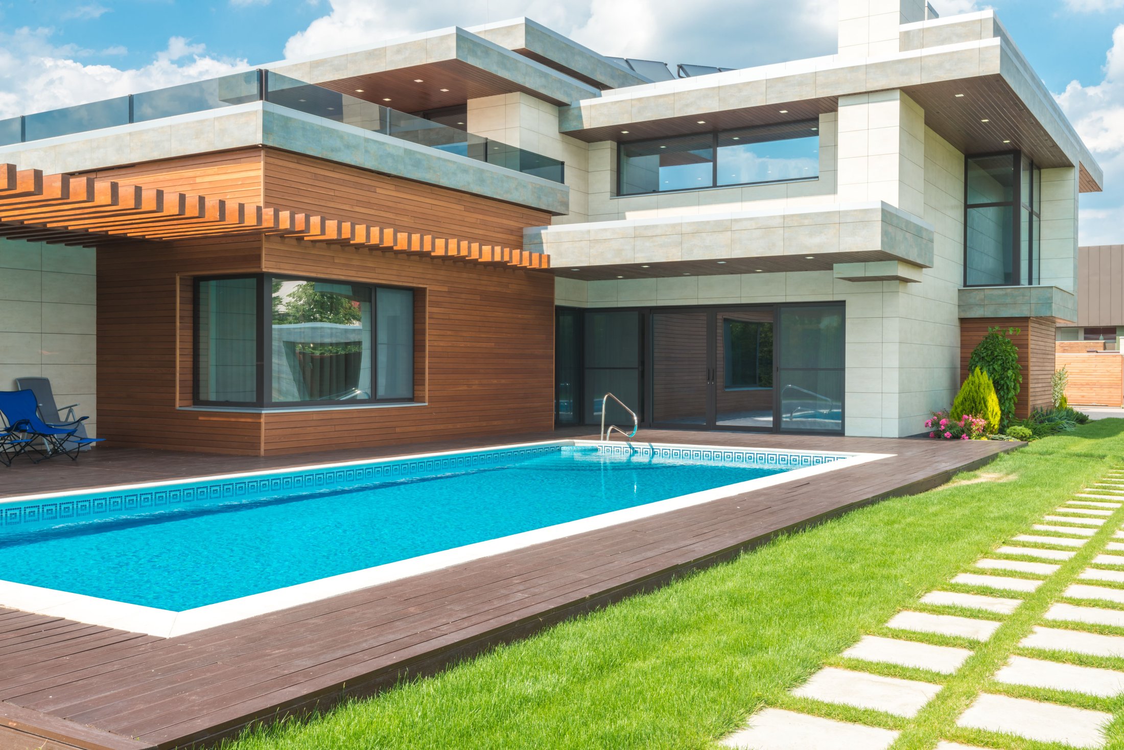 A contemporary residential property photographed with its roof, windows, outdoor space and swimming pool